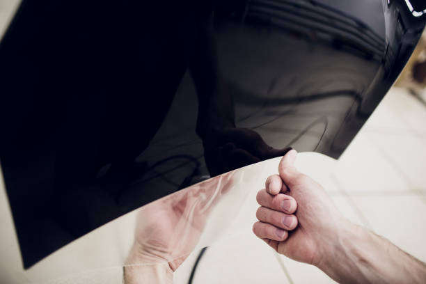 istock Worker hands installs car paint protection film wrap bumper 1147002141