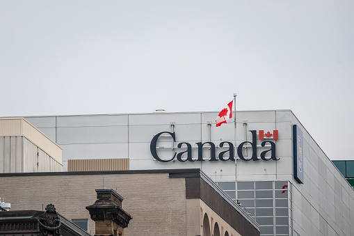 Picture of the flag of Canada on a government building, with the official Canada Wordmark.  Established in 1980, this wordmark is essentially a logo for the government and its institutions