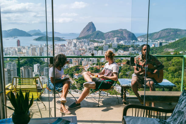 drei freunde auf balkon mit blick auf den zuckerberg - sugarloaf mountain mountain rio de janeiro brazil stock-fotos und bilder