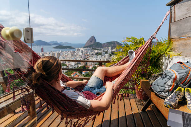 mann in hängematte auf balkon mit blick auf rio de janeiro - brazil rio de janeiro city sugarloaf mountain stock-fotos und bilder