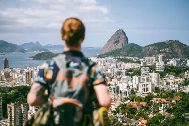 Scenic view across the city of Rio de Janeiro, elevated shot of hiker with backpack looking at view