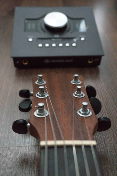 Scene of sound designers tools on dark wood table: sound card, guitar. Sound engineering tools. Professional sound card for music mixing and mastering and classical guitar. Vertical composition escena de herramientas de diseñadores de sonido en la mesa de madera oscura: tarjeta de sonido, guitarra. herramientas de ingeniería de sonido. tarjeta de sonido profesional para mezclar música y masterizar y guitarra clásica. composición vertical