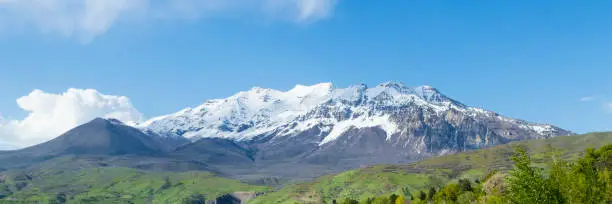 This is a panoramic shot showing Mount Timpanogos in Utah's Wasatch Mountains range.  Mt. Timpanogos is a tall landmark in Utah County, ajoining many of the cities including Provo.  This shot was taken during a wet spring season with the base of the mountain looking very green and the peak covered in snow.