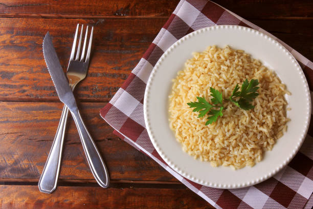 organic brown rice grain cooked in white dish on rustic wooden table. Integral rice Top view stock photo