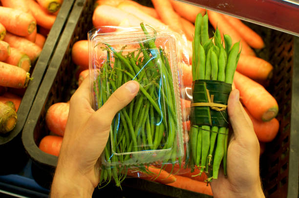 Vegetable wrapped in banana leaves vs. plastic packaging stock photo
