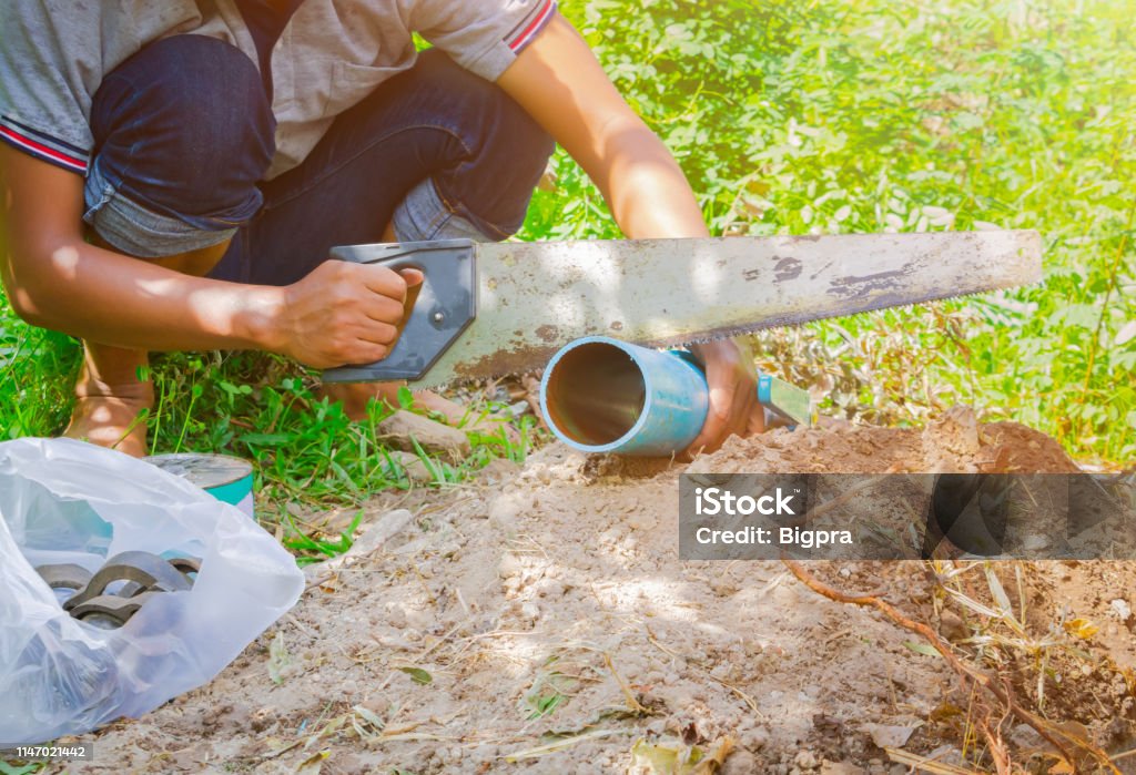 broken pipe in hole and water motion at roadside  plumber working repair and saw On the floor soil with cut saw Adult Stock Photo