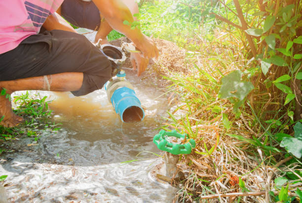istock broken pipe in hole with water motion at roadside and plumber working repair 1147021557