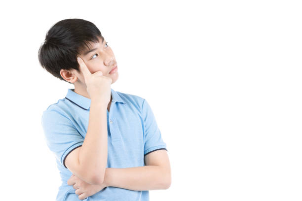 Young Asian boy thinking over white background, Half-length emotional portrait of teen boy wearing blue t-shirt. Thoughtful teenager, isolated on white background. Handsome smart serious ponder child. stock photo