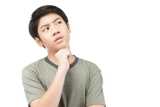 Portrait Young Asian boy over white background, be upset; have a bad temper emotional portrait of teen boy wearing t-shirt. Thoughtful teenager, isolated on white background. stock photo