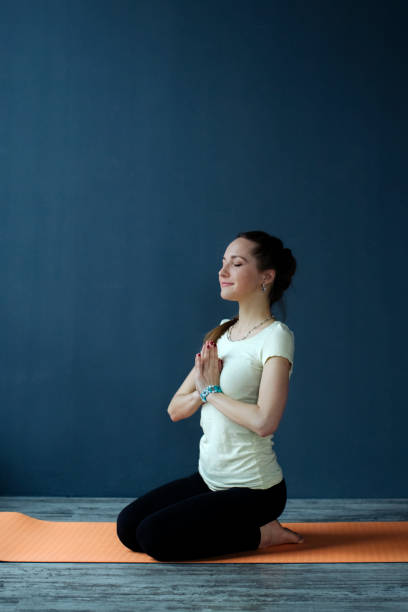 Girl doing yoga with folded palms in prayer namaste sitting on a mat in the yoga studio. soft focus stock photo