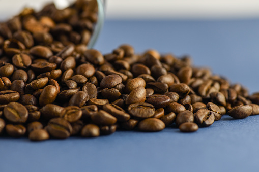 Scattered coffee beans on a blue background. Horizontal photography