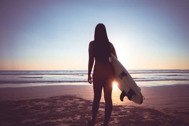 istock woman with surfboard on beach 1147027988