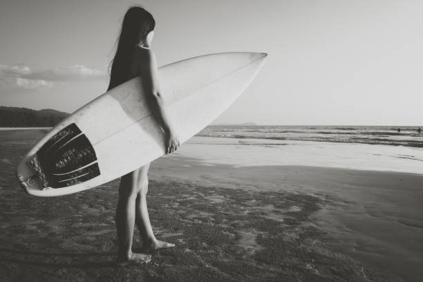 istock woman with surfboard on beach 1147027991