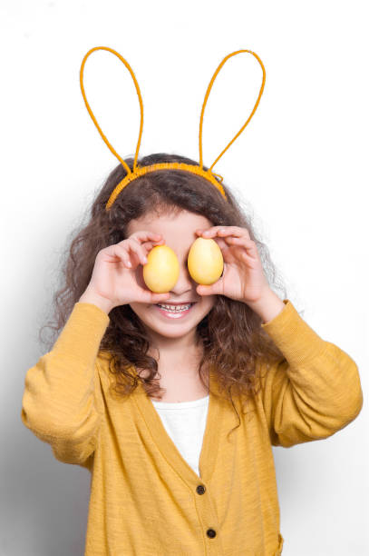 istock Girl with bunny ears with two Easter eggs on a light background. 1147033969