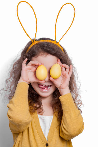 istock Girl with bunny ears with two Easter eggs on a light background. 1147033978
