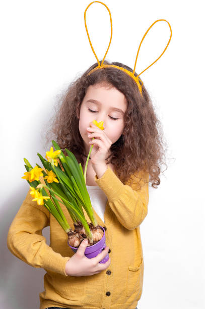istock Girl with bunny ears with flowers on a light background. 1147034062