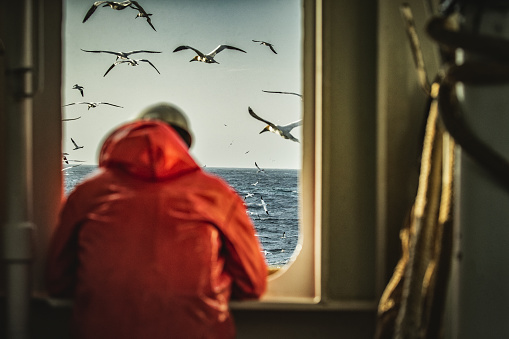 Pescador mirando al mar en la cubierta del barco de pesca photo