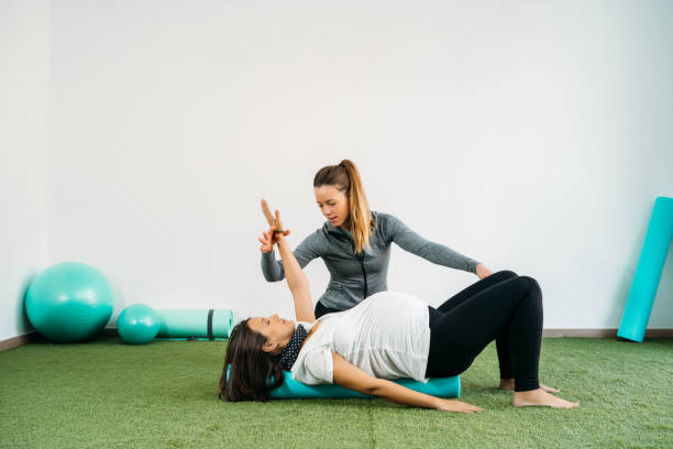 mujer embarazada haciendo ejercicio de fitness ball y pilates con coach. feliz futura madre preparándose para el parto. - human pregnancy yoga exercising prenatal care fotografías e imágenes de stock