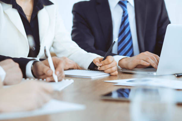 istock Group of business people or lawyers  work together at meeting in office, hands using tablet and making notes close-up. Negotiation and communication concept 1147044708