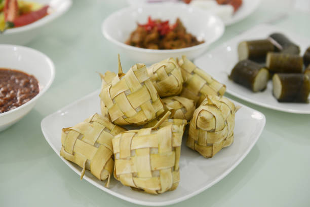 bolo de arroz dentro de folhas de coco tecidas ou ketupat servidas na mesa de jantar - woven bamboo art close up - fotografias e filmes do acervo