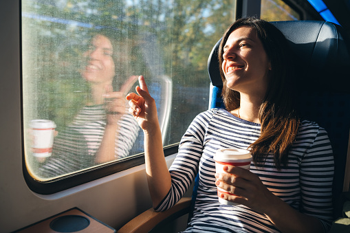 Young woman is admiring the view from in a train window