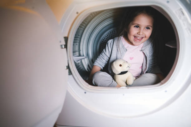 istock Cute child playing in a washing machine 1147060453