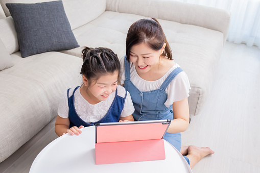 Mom and daughter use tablet happily at home