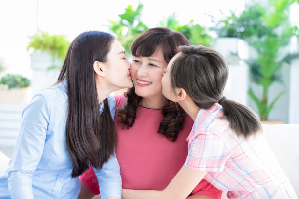 istock two daughters kiss mom at home 1147060851