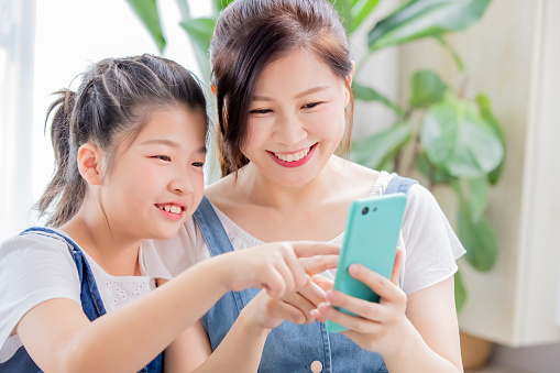 Daughter and mother use smart phone happily at home