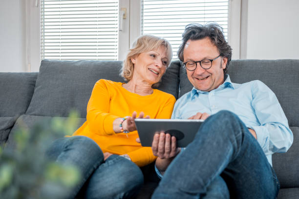 istock Mature caucasian couple sitting on the sofa and using a digital tablet 1147062042