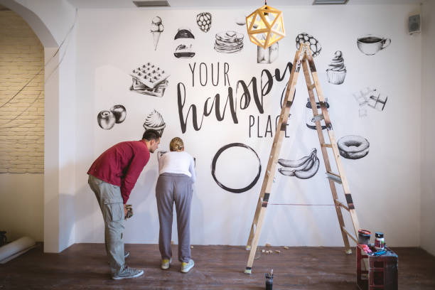 istock Motivated artists painting on the wall together 1147063721