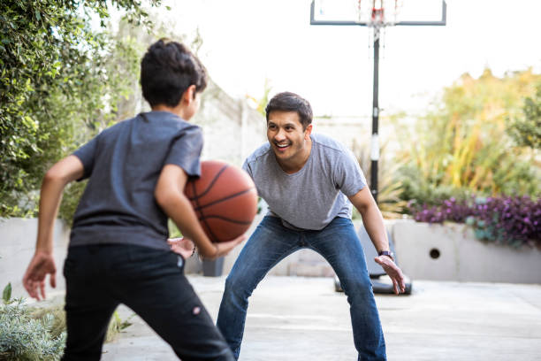 padre hispano e hijo jugando al baloncesto en el patio trasero - bouncing ball family playing fotografías e imágenes de stock