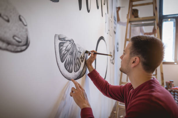 istock Handsome artist painting on the wall 1147067734
