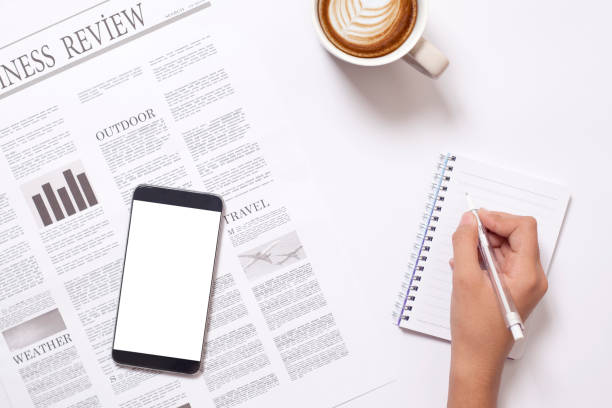 istock hands and newspaper with smartphone over office desk 1147070856