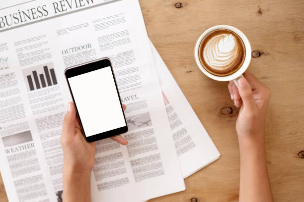 istock hands and newspaper with smartphone over office desk 1147070859