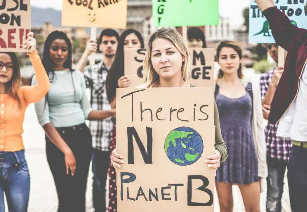 Photo of Group of demonstrators on road, young people from different culture and race fight for climate change - Global warming and enviroment concept - Focus on blond girl face