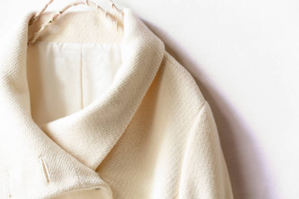 istock white wool coat hanging on clothes hanger on white background 1147077236