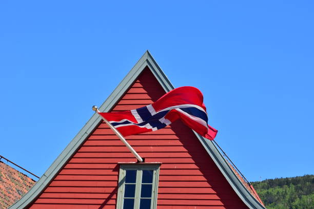 flag of Norway are fluttering in the wind against the blue sky and sea background. Concept of Norwegian Constitution Day.  Celebrated on May 17.