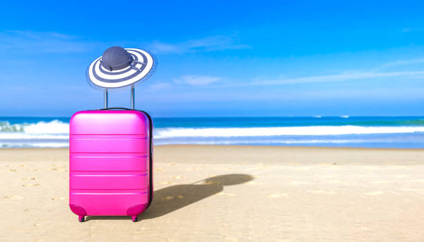 istock Suitcase with sun hat on sea beach. 1147080641