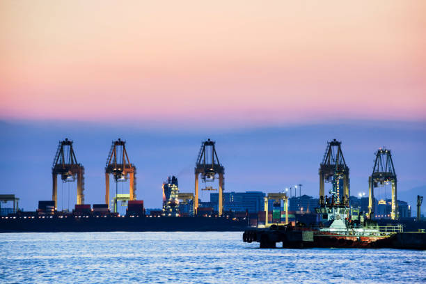 istock Crane for shipping container carrier with sunrise background 1147083313