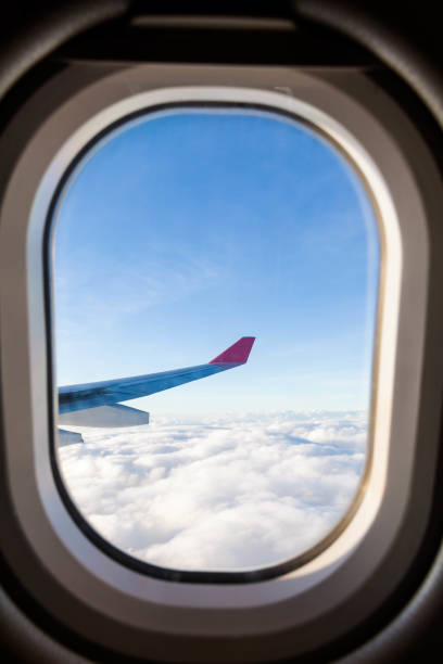 istock Plane wing view from inside plane in midair with blue sky cloud background 1147083541