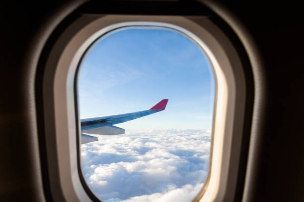 istock Plane wing view from inside plane in midair with blue sky cloud background 1147083545