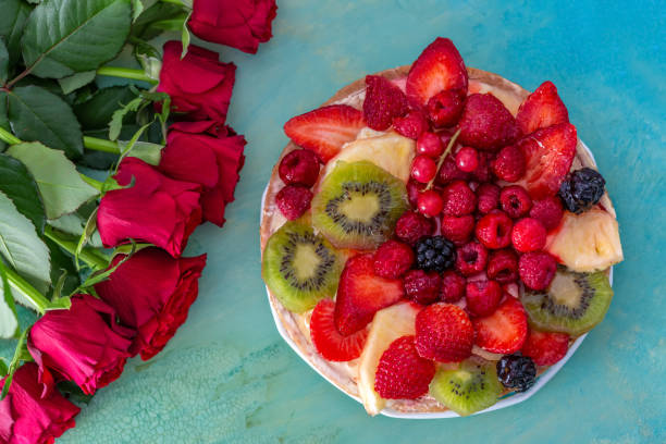 beautiful delicious sweet cake with berries. strawberries, kiwi, currants, blackberries, raspberry, pineapple on the biscuit. fruit variety. dessert. bouquet of roses. soft focus. macro. top view. - biscuit red blue macro imagens e fotografias de stock