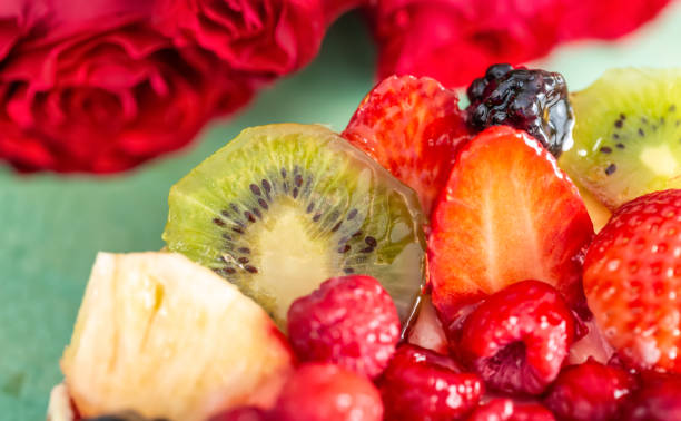 cake with berries. strawberries, kiwi, currants, blackberries, raspberry, pineapple on the biscuit. fruit variety. dessert. bouquet of roses. soft focus. macro. top view. - biscuit red blue macro imagens e fotografias de stock