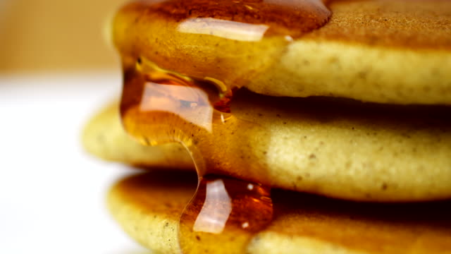 Food Pancake Maple syrup pouring onto stack of pancakes. Close-up turning Homemade Pancake