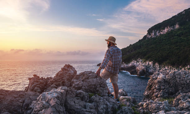 Man stands on rocks and watches sunset