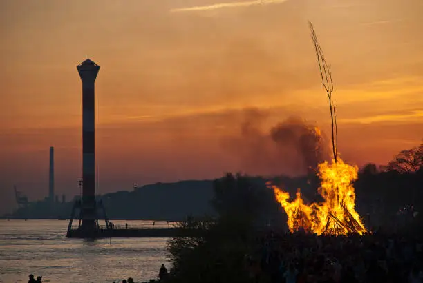Easter fire in the sunset, in the background the lighthouse of Blankenese (Hamburg, Germany). Easter fires have been a tradition in Blankenese for centuries.
