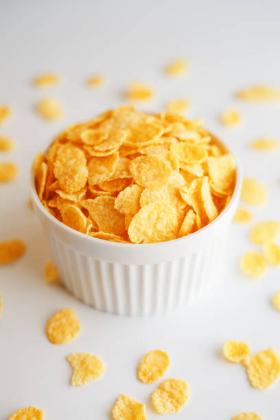 istock White cup with golden corn flakes, isolated on white background. Hopya crumbled around the cup. View from above. Delicious and healthy breakfast 1147089521