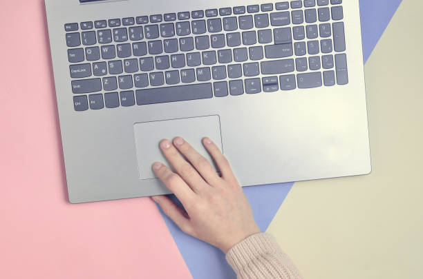 istock A female hand uses a laptop. A minimalist trend. Online work, freelancing, blogging. Top view on a pastel background. 1147091349