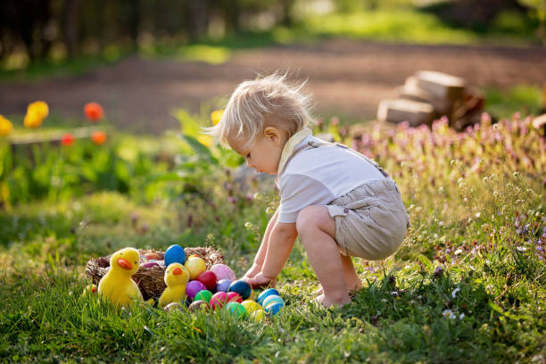 Sweet toddler boy with bunny ears, egg hunting for Easter, child and Easter day traditions. Kids and holidays